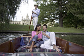 A couple enjoying an early evening river ride on the Cam whilst drinking champagne.